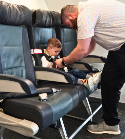 CARES child aviation restraint system fitted to an airline seat, showing the harness securing a toddler safely on a commercial flight.