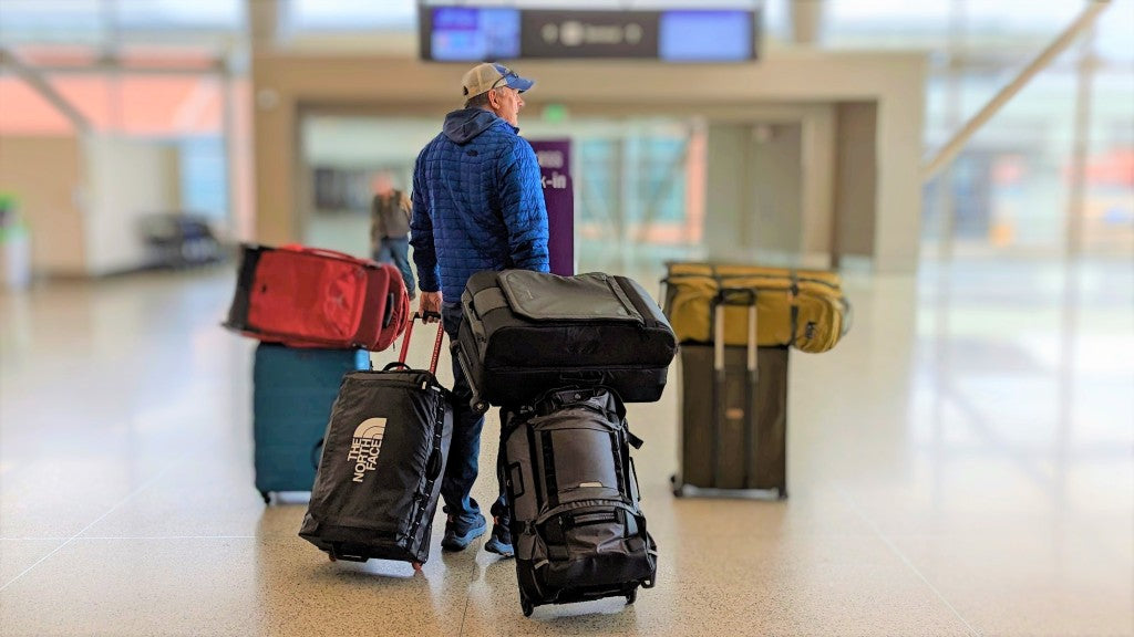 Selection of travel bags for long-haul flights from Australia including anti-theft backpack, carry-on and personal item bag laid out at an airport.