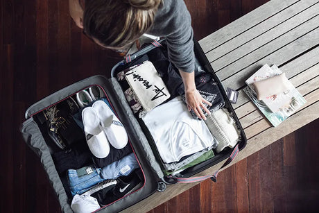 Open suitcase packed efficiently with rolled clothes, packing cubes and travel accessories, demonstrating pro packing techniques for Australian travellers.