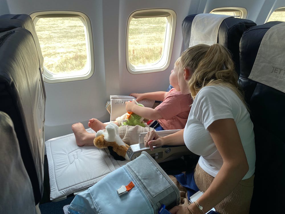 Family with young children navigating an airport with organised carry-on bags and a compact travel stroller, showing stress-free family travel.