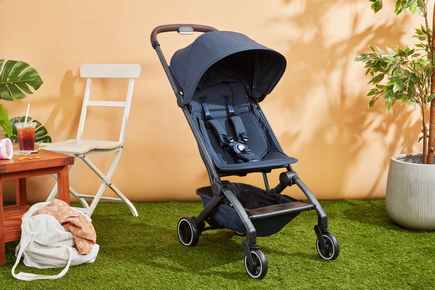 Lightweight travel stroller folded compact next to a carry-on suitcase at an airport, suitable for Australian families travelling with toddlers.