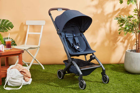 Lightweight travel stroller folded compact next to a carry-on suitcase at an airport, suitable for Australian families travelling with toddlers.