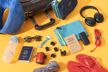 Flat lay of essential travel gear accessories including packing cubes, travel adaptor, RFID wallet, luggage lock and neck pillow for Australian travellers.